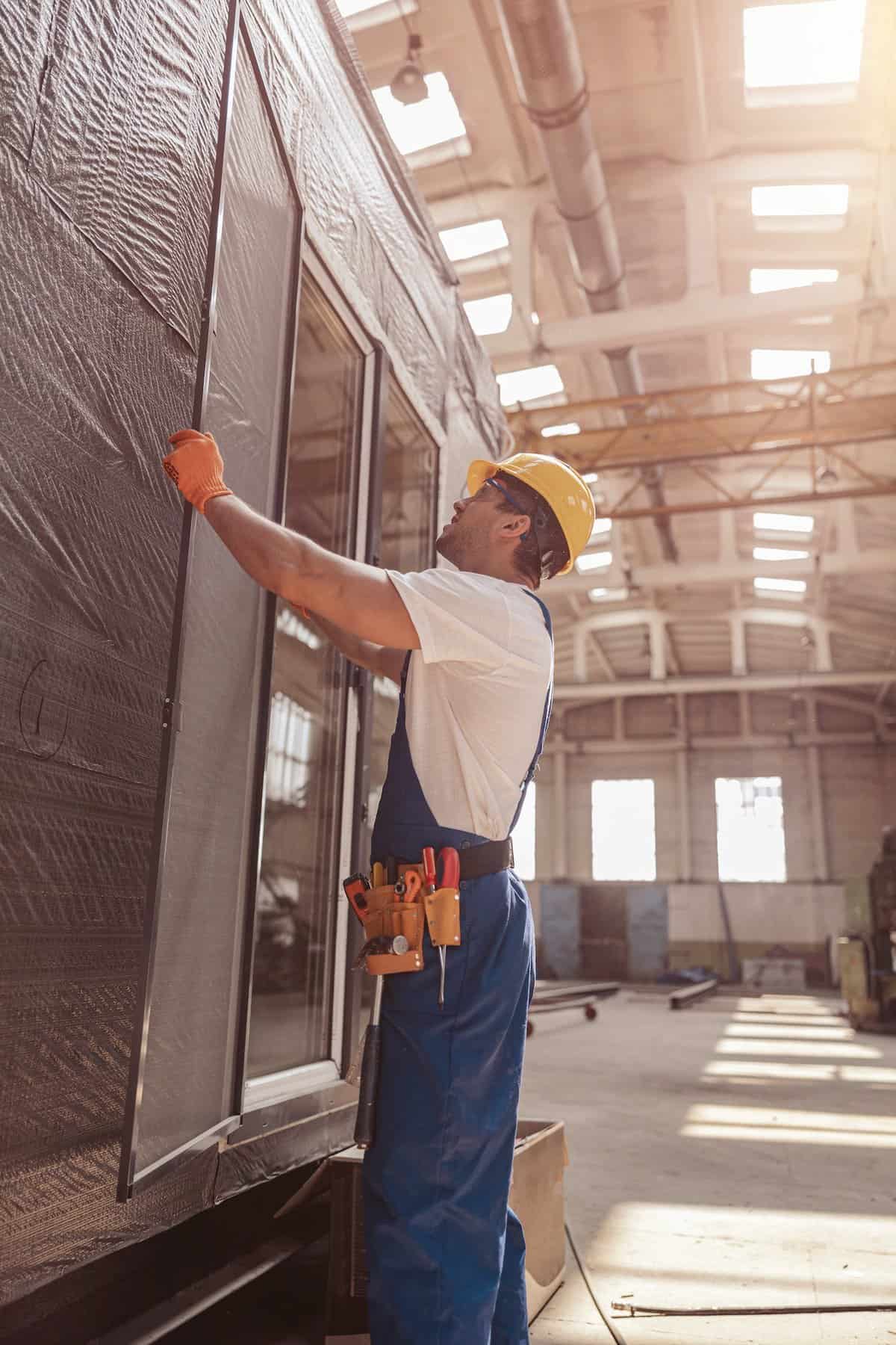 Male builder installing sliding glass door at constriction site